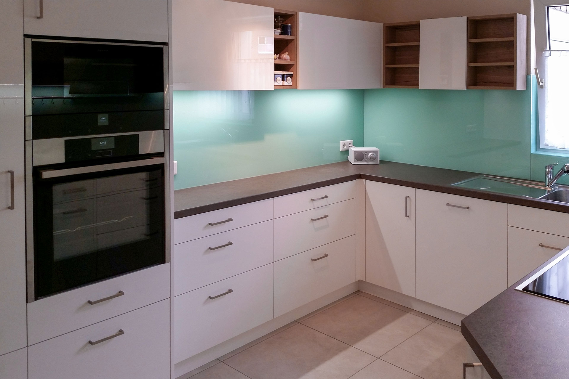 Küche mit Regalelementen für eine luftige Gestaltung und leicht zugänglichen Utensilien, großzügiges Kochfeld, umlaufende Glasrückwand